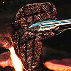 Smoke Yard BBQ grill with brisket smoking over open flame